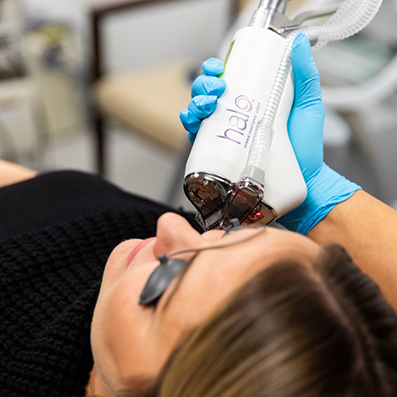 Aesthetic patient having a doctor hold a Halo light laser to her cheek