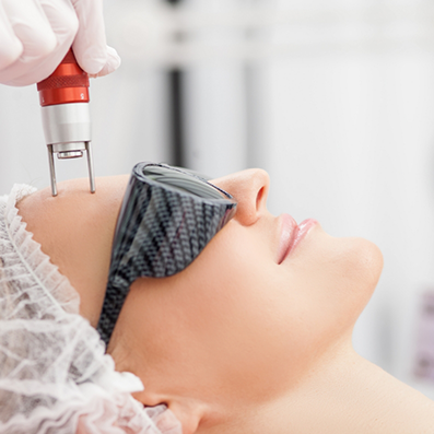 Aesthetic doctor holding a skin rejuvenation laser device to her forehead